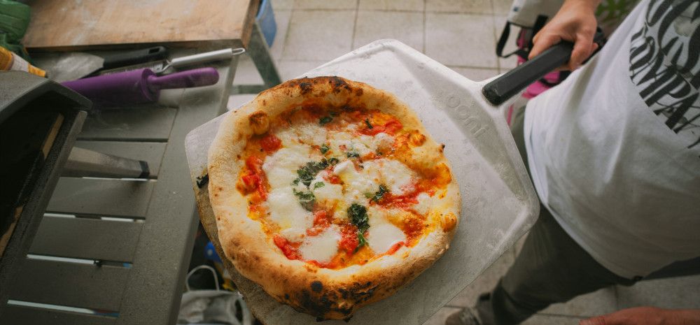 person taking pizza out of oven
