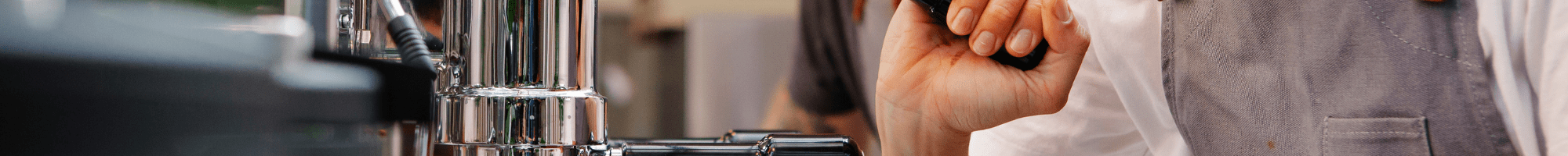 A young person and a trainer behind a coffee machine